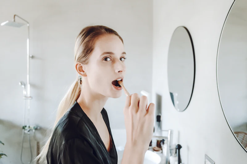 A woman brushing her teeth at the bathroom mirror