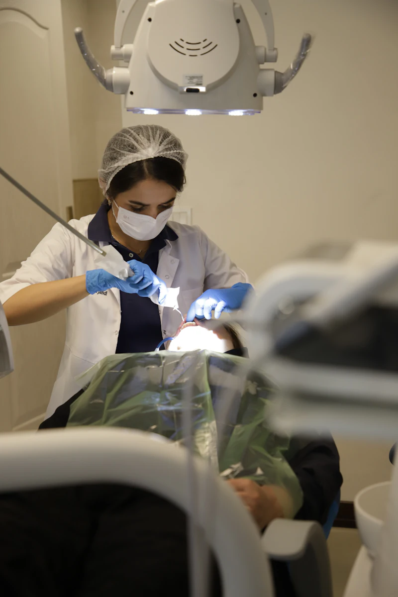 A dentist under the chair light works on a patient's tooth